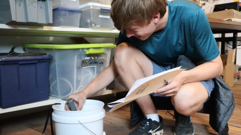 A student makes water measurements with a hand-held sensor.